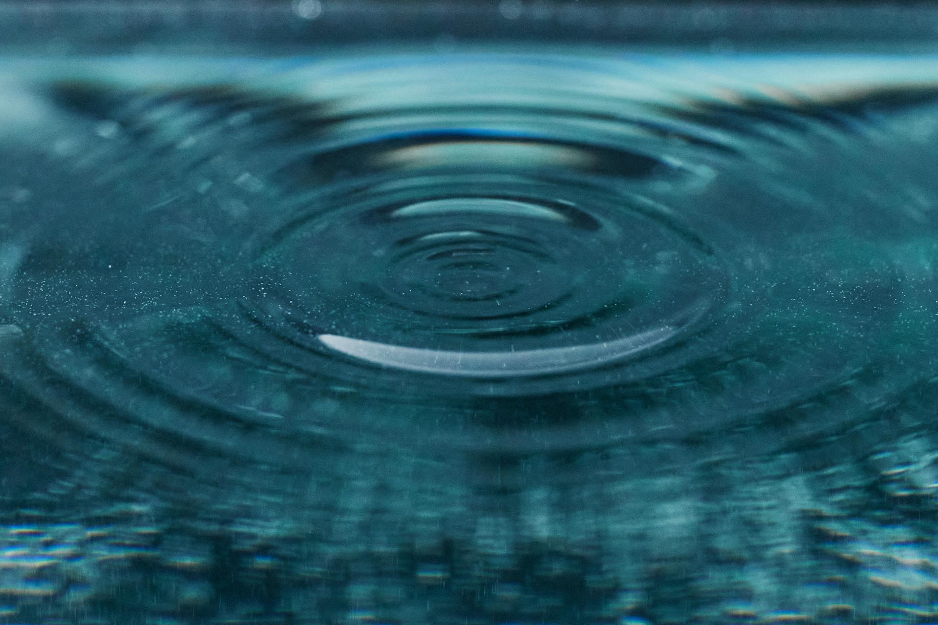 Close-up of clear water with sunlit ripples spreading across the surface.
