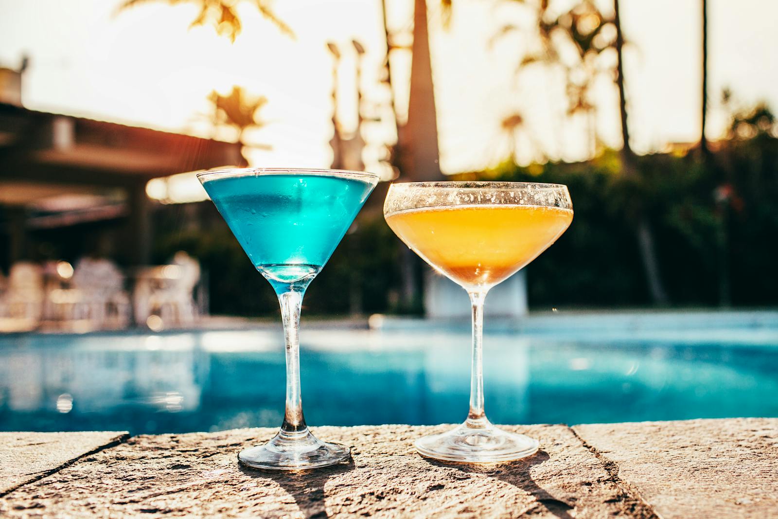 A resort-style pool at sunset with still water and silhouetted palms.